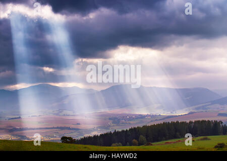 Sonne strahlt über den Wolken im Tatra-Gebirge. Strahlen im bewölkten Himmel Stockfoto