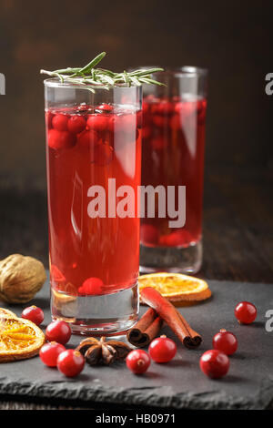 Weihnachten-Cranberry cocktail verziert mit Rosmarin, trockenen Orangenscheiben, Zimtstangen und Anis Sterne Stockfoto