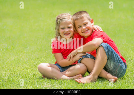 Bruder und Schwester auf Rasen zu umarmen. Stockfoto