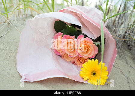 Bukett von Rosen und gelben Gerbera auf dem Sand liegen Stockfoto
