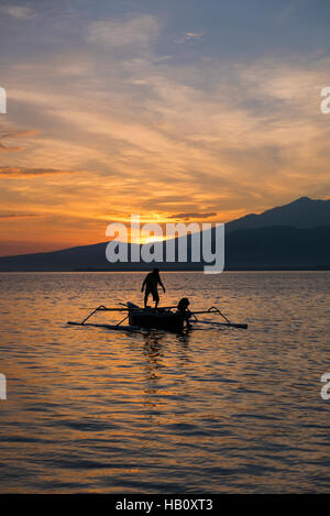 Sonnenuntergang mit Fisher Mann in einem Boot im Meer in der Nähe von Gili Air indonesischen Insel Angeln Stockfoto