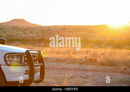 Stoßstange von 4 x 4 SUV mit Berg und Sonnenuntergang im Hintergrund, Namibia Stockfoto