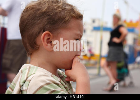 kleiner Junge schreiend auf Festplatz, verärgert Mutter im Hintergrund Stockfoto