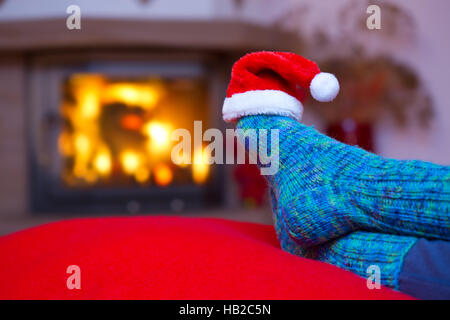 Füße in blauen Wollsocken und Weihnachtsmütze. Stockfoto