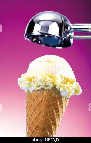 Eiscreme Kegel mit Vanille-Eis, darüber ein Eisportionierer Stockfoto