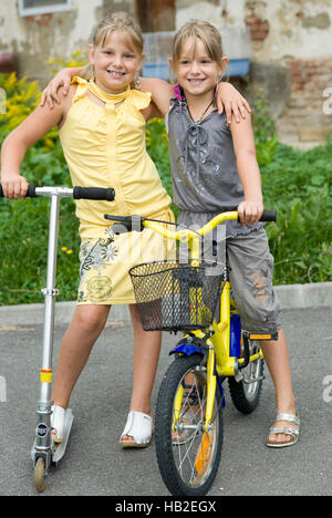 Zwei Mädchen, 8 und 6, mit einen Motorroller und ein Fahrrad Stockfoto