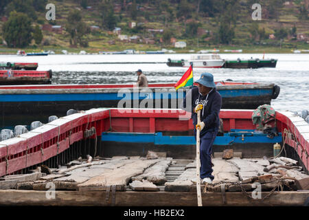 TIQUINA, BOLIVIEN - 12. JANUAR: Junger Erwachsener aus Bolivien, der auf einer Holzfähre über der Straße von Tiquina am Titicacasee arbeitet Stockfoto