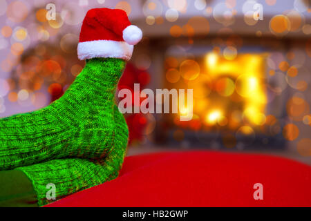 Füße in blauen Wollsocken und Weihnachtsmütze. Stockfoto