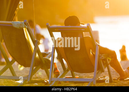 TAGANGA, Kolumbien, JAN 13: Rückansicht des kolumbianischen Tourist in langen Stuhl sitzen und den Sonnenuntergang am Strand genießen. Kolumbien-2014 Stockfoto