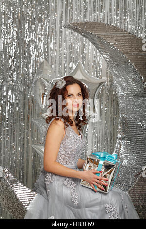 Mädchen im festlichen Kleid hält ein Weihnachtsgeschenk. Die festliche Stimmung. Stockfoto