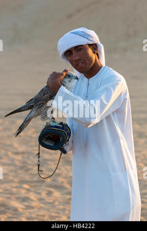 Junge arabische Mann hält ein Falke in der Wüste in der Nähe von Dubai, Vereinigte Arabische Emirate Stockfoto