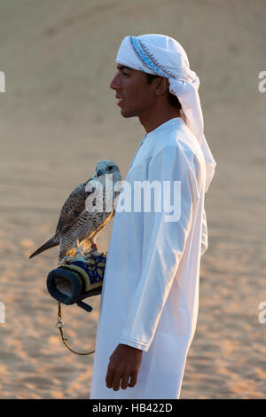 Junge arabische Mann hält ein Falke in der Wüste in der Nähe von Dubai, Vereinigte Arabische Emirate Stockfoto
