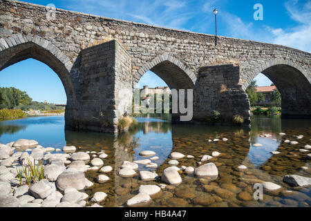 Die romanische Brücke über den Fluss Tormes im El Barco De Avila mit dem Schloss im Hintergrund,, Provinz Ávila, Spanien. Stockfoto