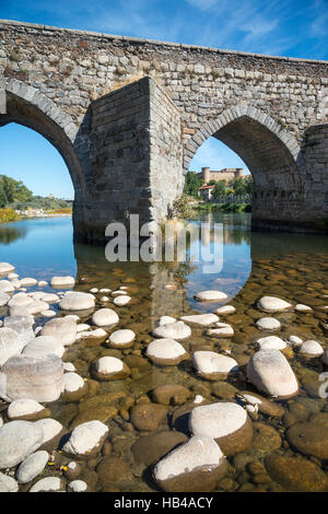 Die romanische Brücke über den Fluss Tormes im El Barco De Avila mit dem Schloss im Hintergrund,, Provinz Ávila, Spanien. Stockfoto