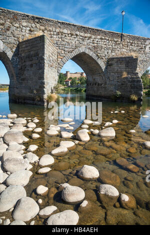 Die romanische Brücke über den Fluss Tormes im El Barco De Avila mit dem Schloss im Hintergrund,, Provinz Ávila, Spanien. Stockfoto