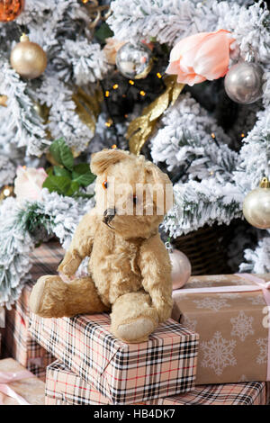 Weihnachtsbaum mit Spielzeugen und Weihnachtsbaum Girlande. Vintage Teddybär sitzend auf den Boxen Stockfoto