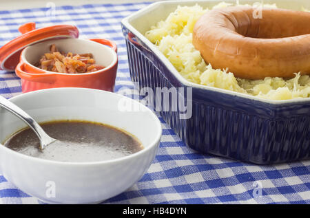 Typische holländische Schale Zuurkool mit Sauerkraut, Speck, geräucherte Wurst und Soße auf einem rustikalen blau Tischdecke Stockfoto