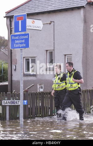 Cumbria Polizisten begehbar durch Hochwasser Sandgate in Kendal, Cumbria am 6. Dezember 2015, Bewohner von den Überschwemmungen betroffenen zu helfen. Stockfoto