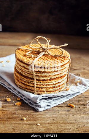 Stapel von traditionellen niederländischen Karamel Waffeln mit Jute Garn auf rustikalen hölzernen Hintergrund, selektiven Fokus gefesselt Stockfoto