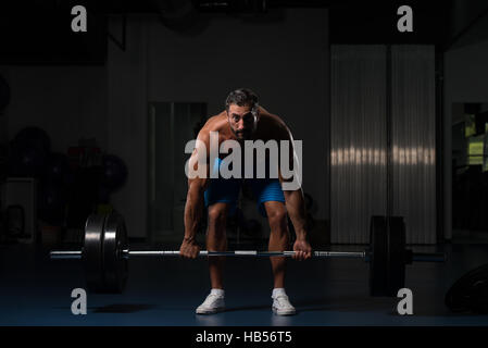 Muskulöser Hispanic Mann schwere Übung für Rücken mit Langhantel im modernen Fitnessraum Stockfoto