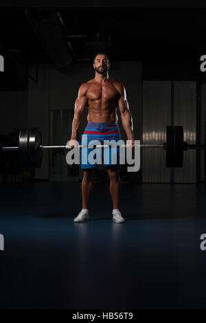 Muskulöser Hispanic Mann schwere Übung für Rücken mit Langhantel im modernen Fitnessraum Stockfoto