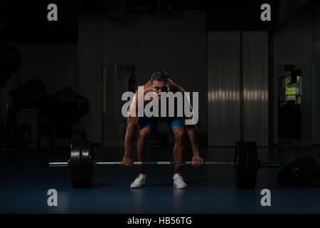 Muskulöser Hispanic Mann schwere Übung für Rücken mit Langhantel im modernen Fitnessraum Stockfoto