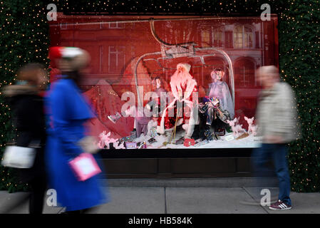 Käufer außerhalb eines Selfridges-Fensters anzeigen auf der Oxford Street in London am ersten Sonntag im Dezember. Stockfoto