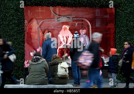 Käufer außerhalb eines Selfridges-Fensters anzeigen auf der Oxford Street in London am ersten Sonntag im Dezember. Stockfoto