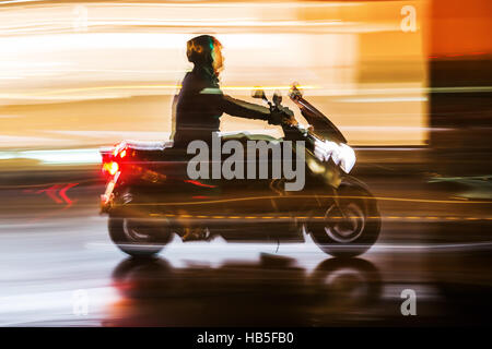 Bild mit der Kamera gemacht Bewegungsunschärfe Effekt ein Motorradfahrer im Nachtverkehr Stockfoto