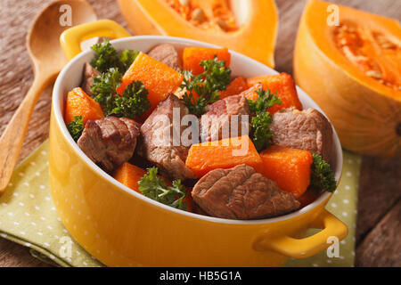 Hausmannskost: Rindsgulasch mit Kürbis Closeup in der gelben Topf auf den Tisch. horizontale Stockfoto