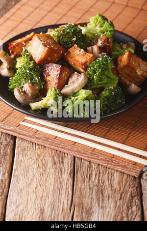 Bohnenkraut sautierten chinesisches Mischgemüse mit knusprig gebratenem Tofu auf dem Teller. Vertikal Stockfoto