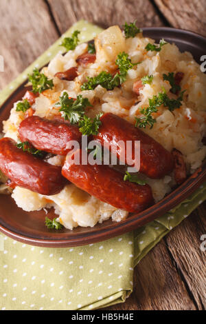 Niederländische Küche: Stamppot aus Kartoffeln, Sauerkraut und Karotten, mit Wurst Nahaufnahme auf dem Tisch. Vertikal Stockfoto