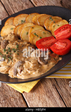 Steak mit Pilzen und Bratkartoffeln Nahaufnahme auf einer Platte. vertikale Stockfoto