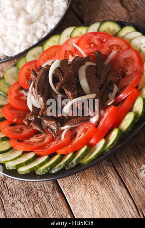 Kambodschanische Rindfleisch Lok Lak mit frischem Gemüse Nahaufnahme auf einer Platte. vertikale Stockfoto