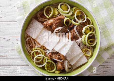 Koreanische Rindfleisch Rippen Suppe, Reisnudeln, Lauch und Daikon hautnah in eine Schüssel geben. Horizontale Ansicht von oben Stockfoto