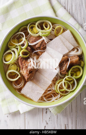 Koreanische Rindfleisch Rippen Suppe, Reisnudeln, Lauch und Daikon hautnah in eine Schüssel geben. vertikale Ansicht von oben Stockfoto