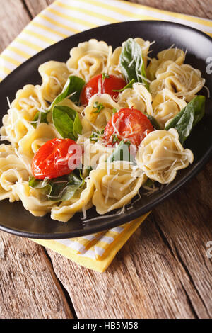 hausgemachte Tortellini mit Spinat, Tomaten und Käse auf einen Teller Nahaufnahme. vertikale Stockfoto