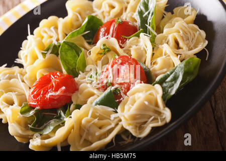 Italienische Tortellini mit Spinat, Tomaten und Parmesan Nahaufnahme auf einer Platte. Horizontale Stockfoto