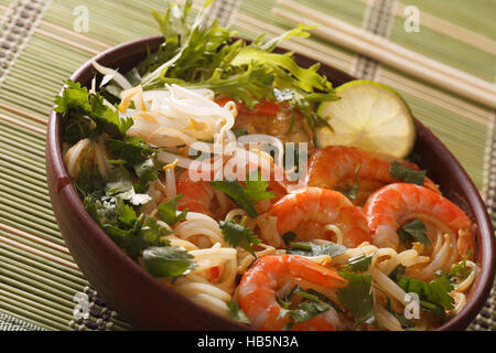 Dicke Suppe mit Garnelen, Nudeln und Kräutern hautnah in einer Schüssel auf dem Tisch. horizontale Stockfoto