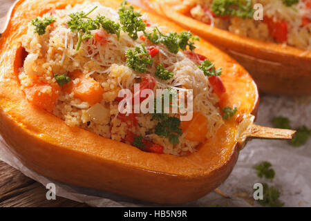 Gebackener Kürbis gefüllt mit Couscous, Fleisch und Gemüse Makro auf dem Tisch. horizontale Stockfoto