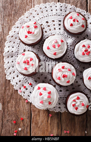 Red Velvet Cupcakes dekoriert mit Herzen Nahaufnahme auf dem Tisch. vertikale Ansicht von oben Stockfoto