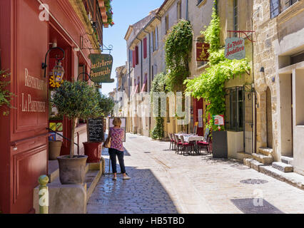 Frau auf der Suche auf einer Speisekarte in einer malerischen Straße innerhalb der mittelalterlichen Stadt Uzès, Gard, Frankreich Stockfoto