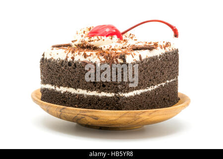 Schokoladenkuchen, garniert mit Kirschen und Sahne in einer hölzernen Platte weiß Stockfoto