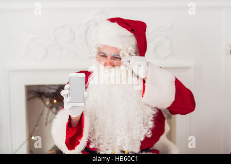 Santa Claus zeigt leeren Bildschirm auf einem Smartphone-display Stockfoto