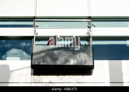 Fensterputzer in einer Gondel außerhalb der Hauptsitz von UBS an Broadgate Kreis, Broadgate, City of London, England, Vereinigtes Königreich Stockfoto