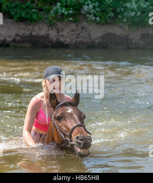 Eine junge Frau reitet ihr Pferd in den Fluss Eden in Appleby Horse Fair in Cumbria, UK Stockfoto