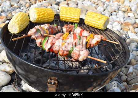 Kleiner Grill am Strand frische Hähnchen-Spieße mit Mais Stockfoto