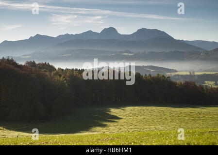 Nebel in den Tälern und bunten herbstlichen Wälder der Bayerischen Alpen mit Mount Wendelstein gesehen vom Mount Irschenberg in der Morgensonne, Deutschland Stockfoto