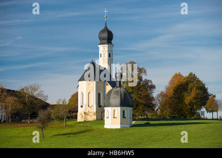 Bunte Fassade, Kirchtürme und Dach der barocken Wallfahrtskirche Wilparting und Kapelle gegen den blauen Himmel in der Morgen Sonne, Bayern, Deutschland Stockfoto