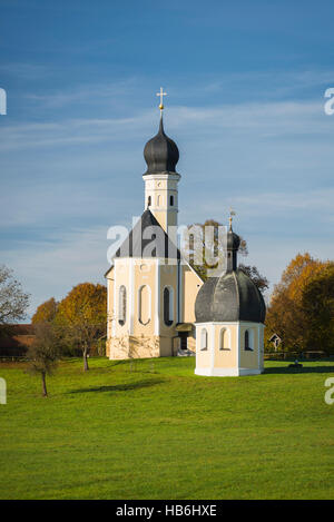 Bunte Fassade, Kirchtürme und Dach der barocken Wallfahrtskirche Wilparting und Kapelle gegen den blauen Himmel in der Morgen Sonne, Bayern, Deutschland Stockfoto